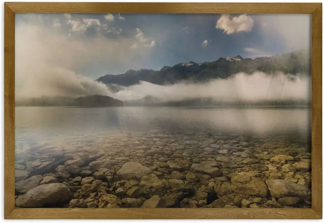 Ambesonne Nature Framed Wall Art, Alpine Lake with Stones Rocks in Crystal Water with Misty Fogy Clouds Image, Fabric Poster with Walnut Tone Wood Frame Home Dorm Decor, 35" x 23", Grey and White